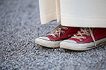 Bilden visar fötter med converse skor och konfirmand i alba 