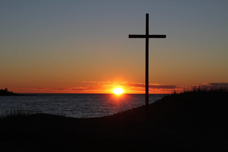 Vacker solnedgång i havet vid stranden i Pörkenäs. Korset i förgrunden.