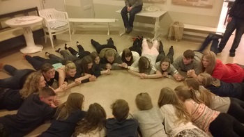 Ungdomar ligger i en ring på golvet.