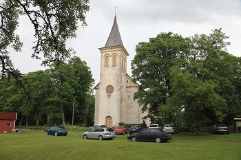 Kyrkan i Hanila, bilar står parkerade utanför på gräsmattan.