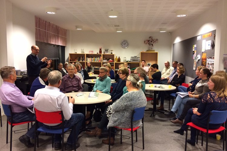 Församlingsmedlemmar sittar runt runda bord och diskuterar
