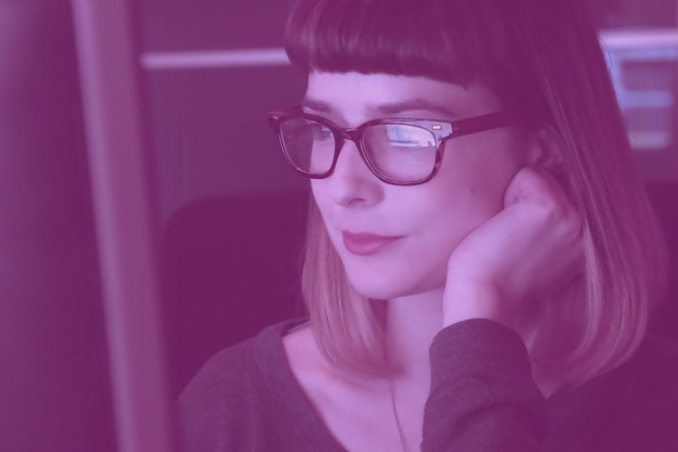 En kvinna med glasögon som ser mot en dataskärm